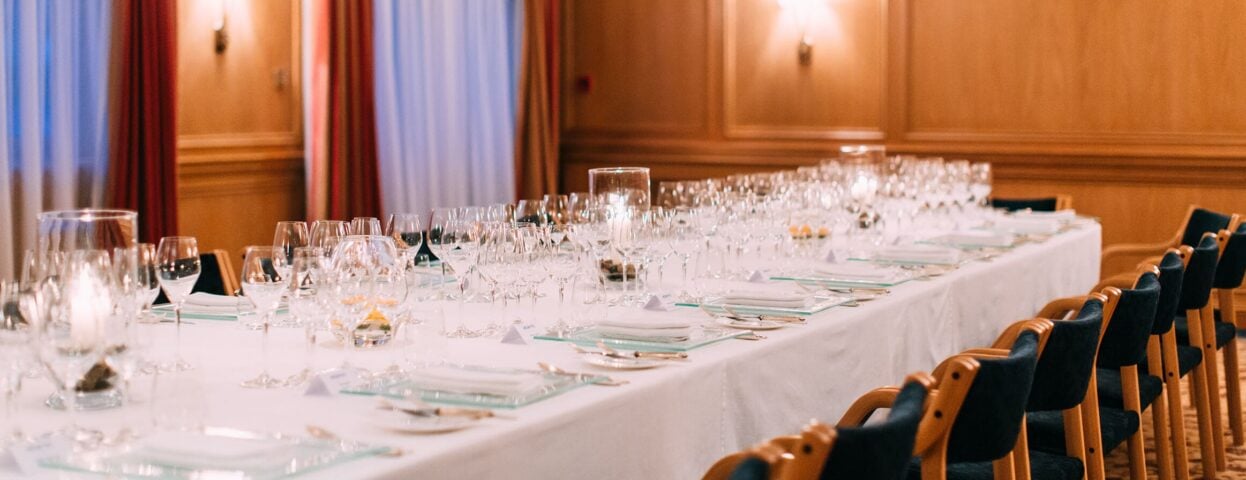 Spacious meeting room at The Atlantic Hotel with rows of chairs, an elegant table, large windows, and modern lighting.